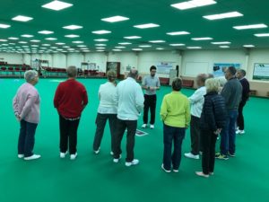 Group of people in an indoor bowls club listening to an instructor